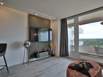 Strandkoje 7: Helles Wohnzimmer mit TV-Wand und Zugang zum Balkon mit Weitblick bis zur Ostsee.