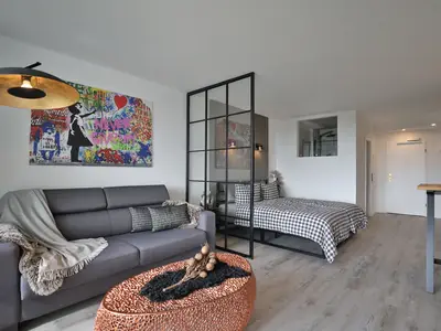 Strandkoje 7: Design trifft Gemütlichkeit – Sofa, Bett und Küche im offenen, hellen Wohnkonzept.