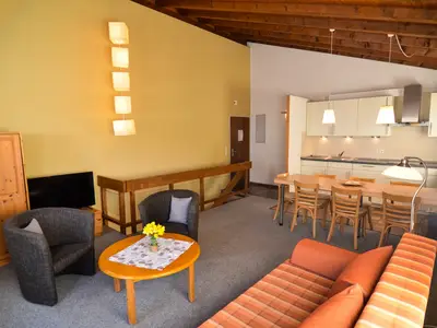 Wohnraum mit großzügiger Küchenzeile, Esstisch, Sessel und Sofa