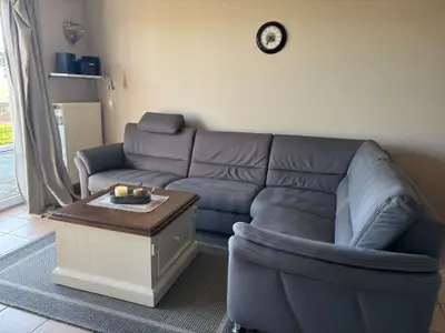 Wohnzimmer mit Eckcouch, Fernseher, DVD-Player und kleiner Musikanlage