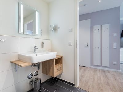 Badezimmer mit Waschtisch und Zugang zum Wohn-/Essbereich