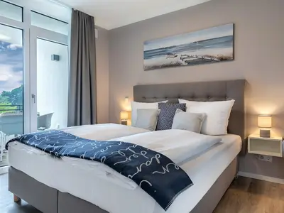 Schlafzimmer mit Boxspringbett und Zugang zur Loggia