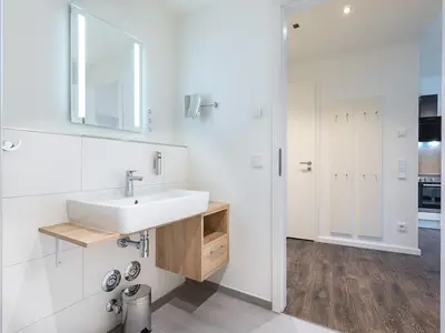 Badezimmer mit Waschtisch und Zugang zum Wohn-Essbereich
