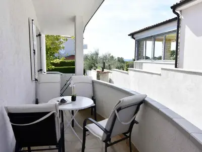 Die überdachte Terrasse ist mit Gartentisch und Stühlen ausgestattet.