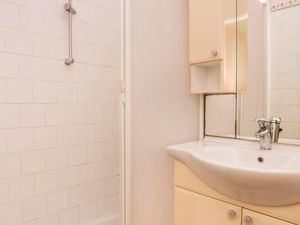 Das Badezimmer mit Dusche, Waschbecken, Schrank und Spiegel