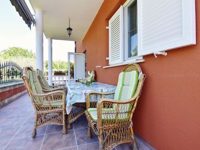 Die überdachte Terrasse ist mit Gartentisch und Stühlen ausgestattet.