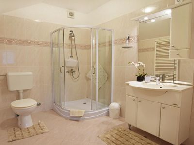 Das Badezimmer hat eine Dusche, Waschbecken mit Schrank und Spiegel, WC