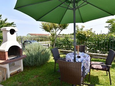 Die private Terrasse mit Grill, Sonnenschirm, Gartentisch und Stühlen ausgestattet