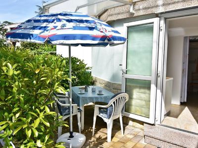 Die private Terrasse am Eingang ist mit Gartentisch und Stühlen und Sonnenschirm ausgestattet.