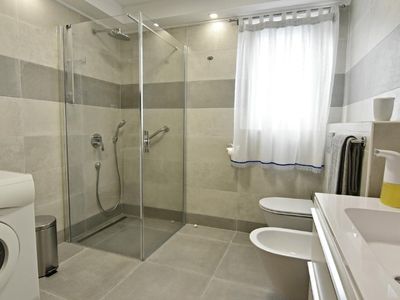 Das Badezimmer verfügt über eine Dusche, eine Waschmaschine, ein Waschbecken, ein Bidet und eine Toilette.