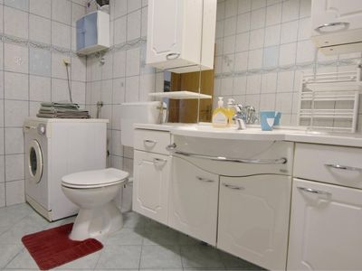 Das Badezimmer hat eine Waschmaschine, Waschbecken mit Schrank und Spiegel, WC.