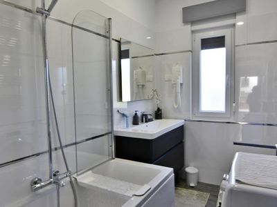 Das Badezimmer mit Badewanne/Dusche, Waschbecken mit Spiegel und Schrank Haartrockner, Bidet, Toilette und Waschmaschine