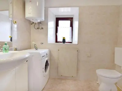 Das Badezimmer mit Waschbecken, Waschmaschine, Außenfenster