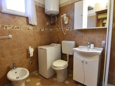 Das Badezimmer verfügt über ein Waschbecken mit Schrank und Spiegel, Bidet, Toilette und Waschmaschine.