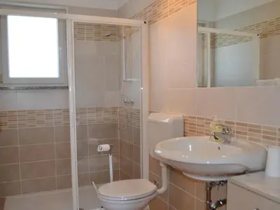 Das Badezimmer mit Dusche, WC, Waschbecken und Spiegel