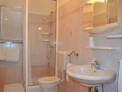 Das Badezimmer mit Dusche, WC, Waschbecken und Spiegel