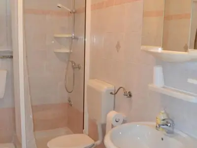 Das Badezimmer mit Dusche, WC, Waschbecken und Spiegel