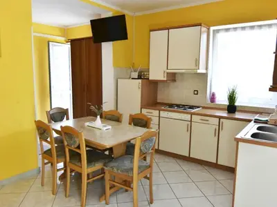 Die Küche ist mit Kühlschrank, Herd, Esstisch und Stühlen ausgestattet