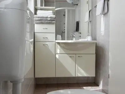 Das Badezimmer hat ein Waschbecken mit Schrank und Spiegel, WC.