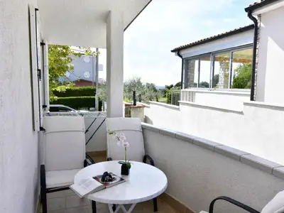 Die Terrasse ist mit Gartenstühlen und Tisch ausgestattet und bietet einen entfernten Meerblick.