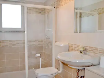 Das Badezimmer mit Dusche, WC, Waschbecken und Spiegel