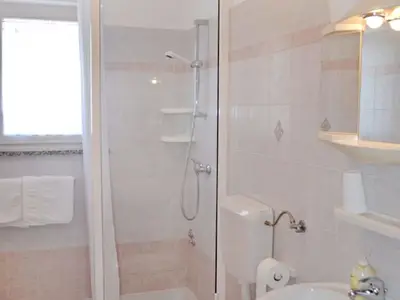 Das Badezimmer mit Dusche, WC, Waschbecken und Spiegel