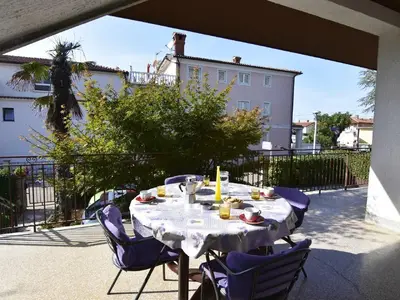Die große überdachte Terrasse mit Tisch und 4 Stühlen mit Blick auf den Garten