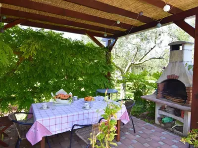 Der Pavillon mit Gartentisch und Stühlen und Grill ausgestattet