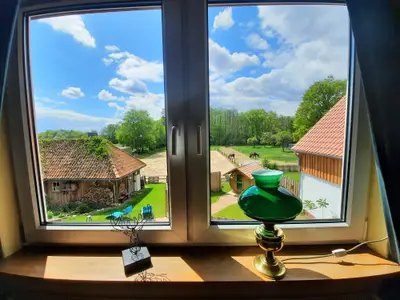 Blick aus dem Wohnzimmer in den Hinterhof und auf den Reitplatz und die Weide