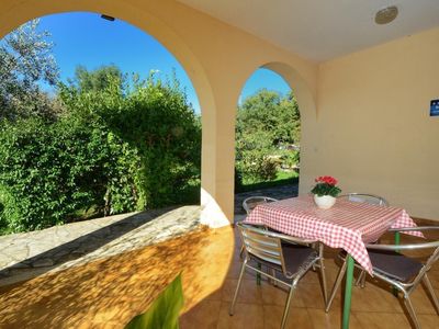 Die große Terrasse am Eingang mit Tisch und Stühlen mit Blick in den Garten.