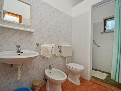 Das Badezimmer ist mit Waschbecken, Spiegel, Bidet, WC und Dusche ausgestattet.