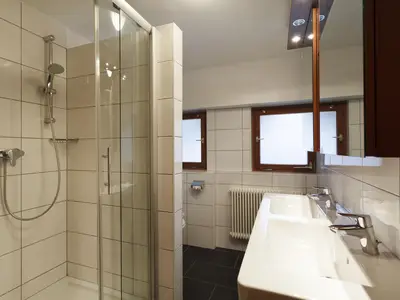 Badezimmer mit Dusche Doppelwaschbecken und WC