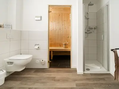 Badezimmer mit Sauna und ebenerdiger Dusche