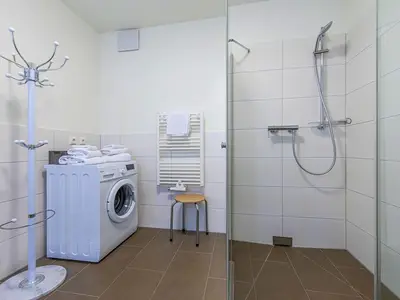 Ferienwohnung MüritzKieker Hafenresidenz: Badezimmer mit Glasdusche und Waschmaschine