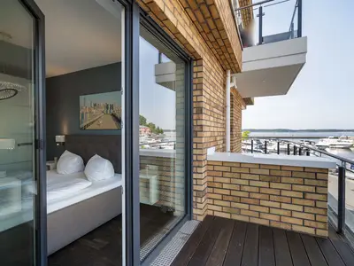 Ferienwohnung First Marina View Waren (Müritz) - Schlafzimmer mit Zugang zum Balkon und traumhaftem Hafenblick