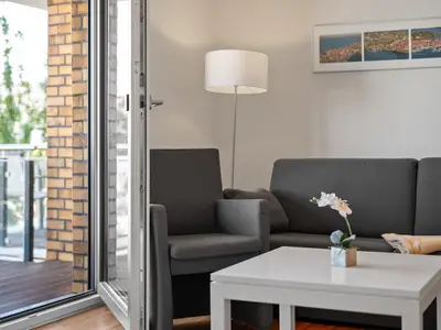 Ferienwohnung Hafenblick Waren (Müritz) – Helles Wohnzimmer mit Zugang zum Balkon und gemütlicher Sitzecke