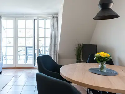 ein runder Esstisch mit vier Stühlen steht im Wohnzimmer der Ferienwohnung Carmen App. 12 in Wenningstedt