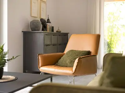 Wohnzimmer mit Ledersessel und grünem Kissen