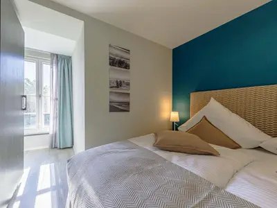 Ferienwohnung Lüttkoje Ostseebad Wustrow – helles Schlafzimmer mit gemütlichem Doppelbett und maritimer Akzentwand