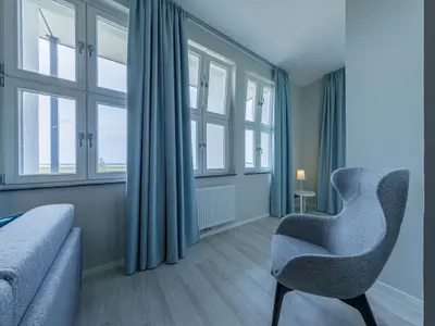 Ferienwohnung Panorama-Utkiek in Wustrow – Heller Wohnbereich mit großen Fenstern, Sitzbereich und Blick ins Grüne