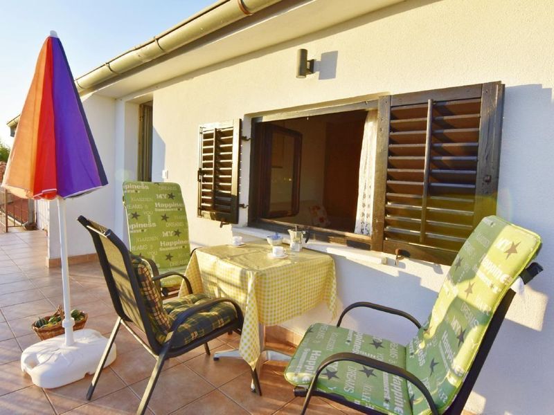Die Terrasse mit Gartentisch und Stühlen, Sonnenschirm ausgestattet.