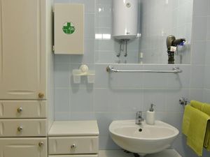 Das Badezimmer verfügt über ein Waschbecken mit Schrank und Spiegel.