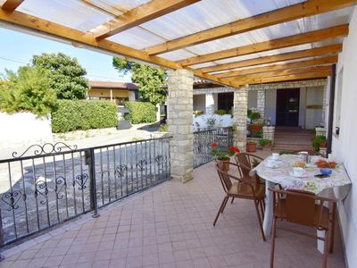 Die Terrasse mit Tisch und 4 Stühlen am Eingang, eingezäunt mit einem Tor