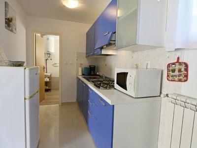 Die Küche mit Herd, Mikrowelle, Kühlschrank mit Gefrierfach, Zugang zum Badezimmer