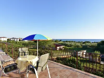 Die Terrasse mit Tisch, Stühlen und Sonnenschirm bietet einen spektakulären Meerblick
