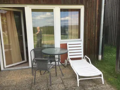 möblierte Terrasse mit Liegestuhl und Gartengrill