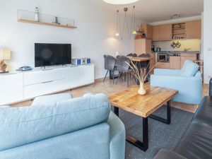 Wohnzimmer mit Sofa, Sesseln und blick in die offene Küche