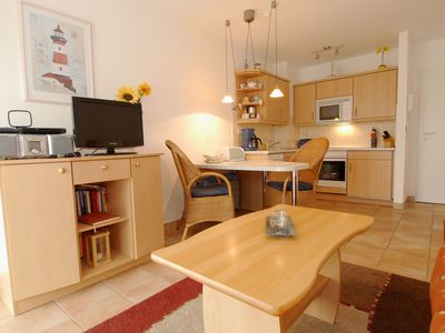 Wohnbereich mit Sideboard und TV, Blick in die offene Küche mit Esstisch und Bestuhlung