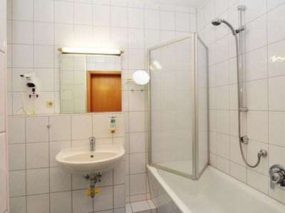 Badezimmer mit Waschbecken, WC, Spiegel und Badewanne mit Dusche