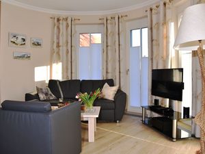 Wohnbereich mit Couch, Sessel, Couchtisch und Sideboard mit TV